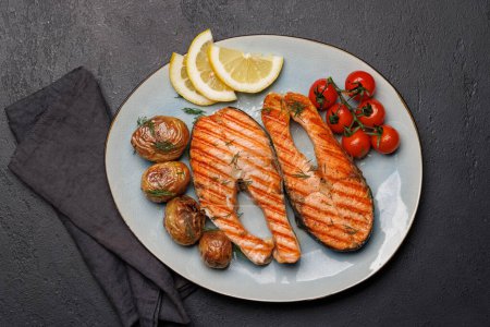 Photo for Grilled salmon steaks and potatoes on a plate, a mouthwatering delight - Royalty Free Image