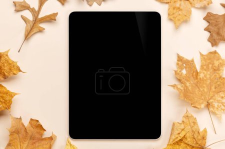 Photo for Tablet with blank screen on a table surrounded by autumn nature leaves, perfect design mockup - Royalty Free Image