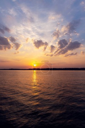 Téléchargez les photos : Une vue imprenable sur le coucher du soleil sur une rivière, mettant en valeur la beauté de la nature et la tranquillité du moment - en image libre de droit