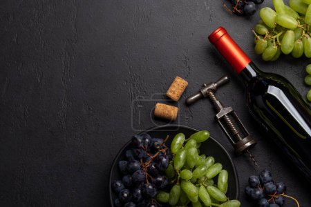 Foto de Una vista superior de una botella de vino, uvas, sacacorchos y tapones de vino en una mesa, con un montón de espacio abierto para el texto. Puesta plana - Imagen libre de derechos