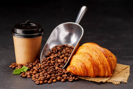 Photo for Aromatic coffee in a paper cup paired with a flaky croissant and fresh roasted beans. With copy space - Royalty Free Image