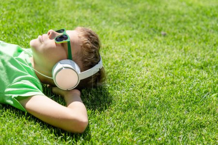 Foto de Un chico relajándose en la hierba, escuchando música con auriculares - Imagen libre de derechos