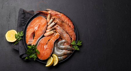 Photo for A top view of fresh seafood such as shrimp, langoustines, and trout steaks. Flat lay with copy space - Royalty Free Image