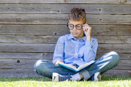 Photo for A boy reading a book on a grassy field. Flat lay with copy space - Royalty Free Image