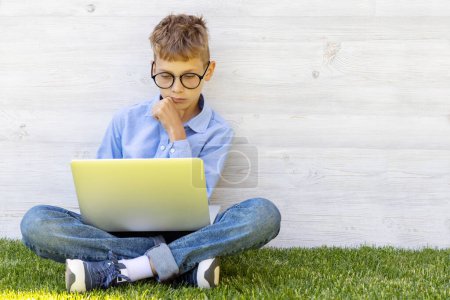 Foto de Un chico usando un portátil al aire libre. Concepto de educación o entretenimiento - Imagen libre de derechos