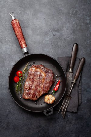 Photo for Grilled ribeye beef steak in frying pan with herbs and spices. Flat lay with copy space - Royalty Free Image