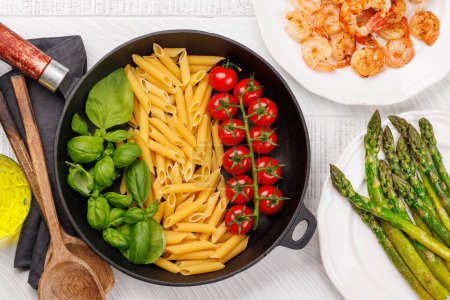 Téléchargez les photos : Une représentation vibrante du drapeau italien fait avec des pâtes, du basilic et des tomates, magnifiquement présenté dans une poêle. Pose plate - en image libre de droit