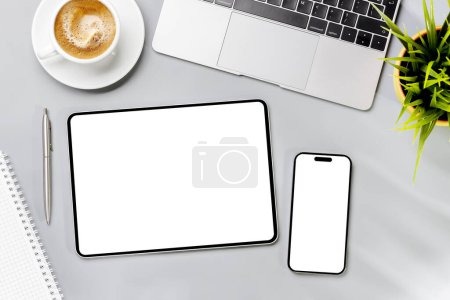 Foto de Tableta y smartphone con pantalla en blanco en el escritorio de la oficina de negocios. Espacio de trabajo plano con luz soleada y espacio de copia - Imagen libre de derechos