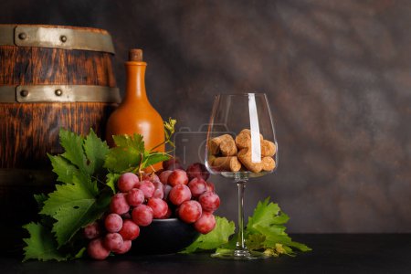 Téléchargez les photos : Bouteille de vin, verre avec bouchons de vin et raisins luxuriants, mettant en valeur l'art de la vinification. Avec espace de copie - en image libre de droit