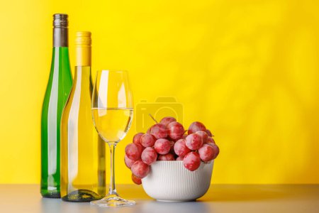Téléchargez les photos : Bouteilles de vin et raisins luxuriants, mettant en valeur l'art de la vinification. Avec espace de copie - en image libre de droit