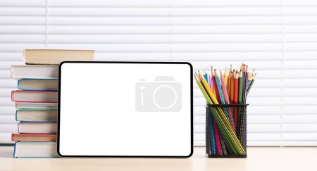 Foto de Tableta con lápices de colores y pila de libros. Con pantalla en blanco para su texto o aplicación - Imagen libre de derechos