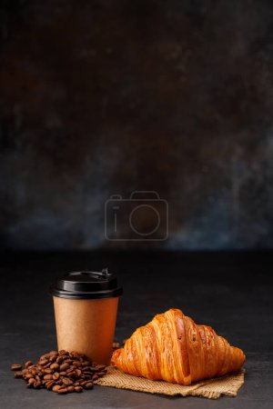 Téléchargez les photos : Café aromatique dans une tasse en papier associée à un croissant floconneux. Avec espace de copie - en image libre de droit