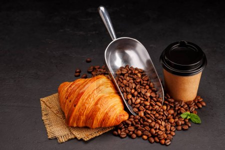 Foto de Café aromático en una taza de papel emparejado con un croissant escamoso y frijoles asados frescos. Con espacio de copia - Imagen libre de derechos