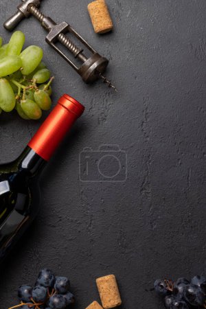 Téléchargez les photos : Une vue de dessus d'une bouteille de vin, raisins, tire-bouchon et bouchons de vin sur une table, avec beaucoup d'espace ouvert pour le texte. Pose plate - en image libre de droit