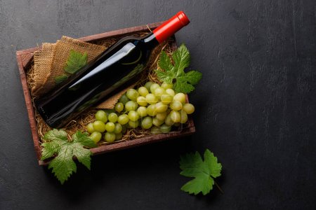 Foto de Botella de vino tinto y uvas frescas, presentadas en una caja de madera rústica. Piso con espacio de copia - Imagen libre de derechos