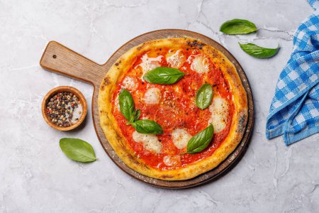 Foto de Pizza de margarita casera, cubierta con tomates frescos, queso mozzarella y hojas aromáticas de albahaca. Puesta plana - Imagen libre de derechos