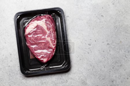 Foto de Vacuum packed beef steak. Raw ribeye steak. Top view flat lay with copy space - Imagen libre de derechos