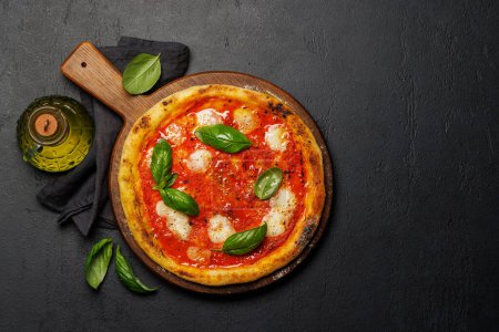Foto de Pizza de margarita casera, cubierta con tomates frescos, queso mozzarella y hojas aromáticas de albahaca. Piso con espacio de copia - Imagen libre de derechos