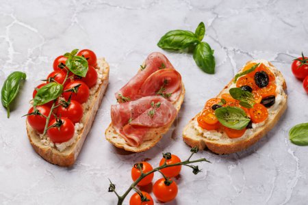 Téléchargez les photos : Un délicieux sandwich à la bruschetta orné de tomates juteuses, de fromage et de prosciutto salé - en image libre de droit