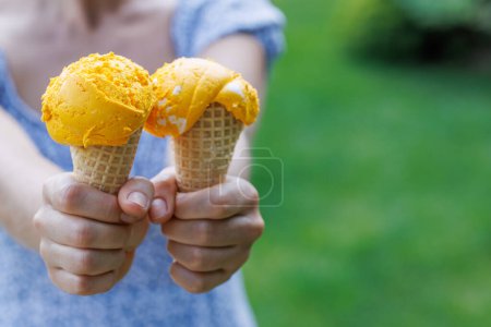 Foto de Las manos de la mujer sosteniendo refrescante helado en conos de gofre trata con un toque de sabor a limón picante. Con espacio de copia - Imagen libre de derechos