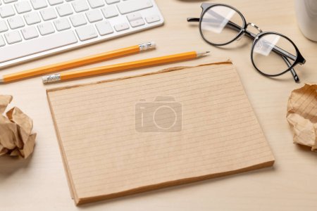 Foto de Vista superior de bloc de notas en blanco, teclado, café y papeles arrugados en el escritorio, que representa intentos infructuosos de escritura - Imagen libre de derechos