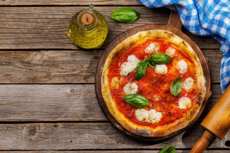 Téléchargez les photos : Pizza margarita maison, garnie de tomates fraîches, de fromage mozzarella et de feuilles de basilic aromatiques. Sur la table de jardin extérieure à plat avec espace de copie - en image libre de droit