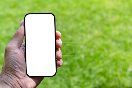 Foto de Smartphone de pantalla blanca en blanco en la mano de la mujer, maqueta de diseño perfecto. Campo de césped soleado al aire libre en el telón de fondo - Imagen libre de derechos