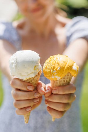 Téléchargez les photos : Mains de femme tenant de la crème glacée rafraîchissante dans des cônes de gaufre friandises avec un soupçon de saveur citronnée - en image libre de droit