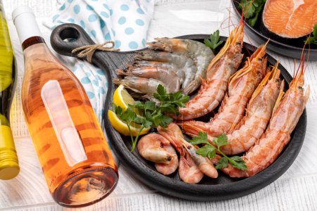 Foto de Una vista superior de mariscos frescos como camarones, langostinos y filetes de trucha, acompañados de vino blanco y rosa - Imagen libre de derechos