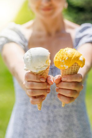 Téléchargez les photos : Mains de femme tenant de la crème glacée rafraîchissante dans des cônes de gaufre friandises avec un soupçon de saveur citronnée - en image libre de droit