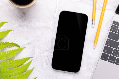 Téléchargez les photos : Smartphone avec écran blanc sur une table entourée de feuilles vertes de la nature, maquette de conception parfaite - en image libre de droit