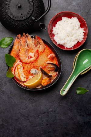 Photo for Traditional Thai soup Tom Yum kung with seafood, coconut milk and chili pepper and rice bowl. Top view flat lay with copy space - Royalty Free Image