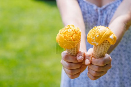 Photo for Woman's hands holding refreshing ice cream in waffle cones treats with a hint of zesty lemon flavour. With copy space - Royalty Free Image