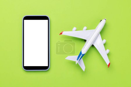 Foto de Concepto de viaje y reserva en línea. Smartphone y juguete de avión en escritorio verde con espacio de copia - Imagen libre de derechos