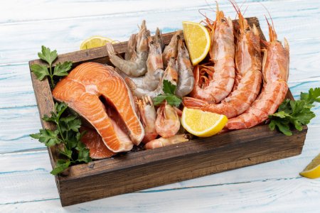 Téléchargez les photos : Une vue de dessus des fruits de mer frais tels que les crevettes, langoustines, et steaks de truite dans la boîte en bois - en image libre de droit