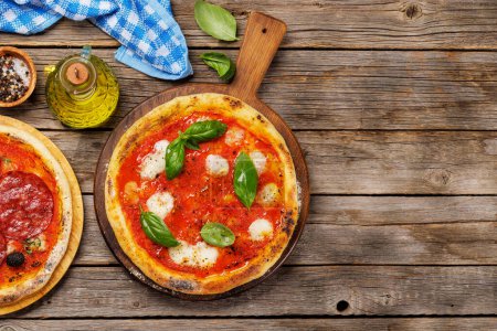 Photo for Homemade margarita pizza, topped with fresh tomatoes, mozzarella cheese, and aromatic basil leaves. On outdoor garden table flat lay with copy space - Royalty Free Image