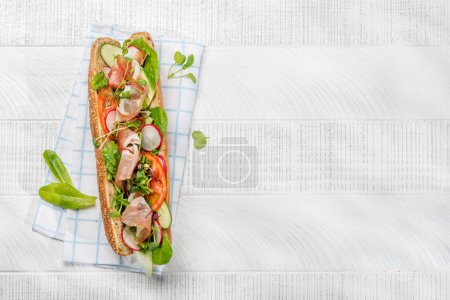 Photo for Delicious sandwich stuffed in a fresh baguette, bursting with flavor and wholesome ingredients. Flat lay with copy space - Royalty Free Image