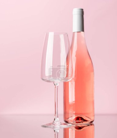 Photo for Rose wine bottle and wine glass over rose background - Royalty Free Image