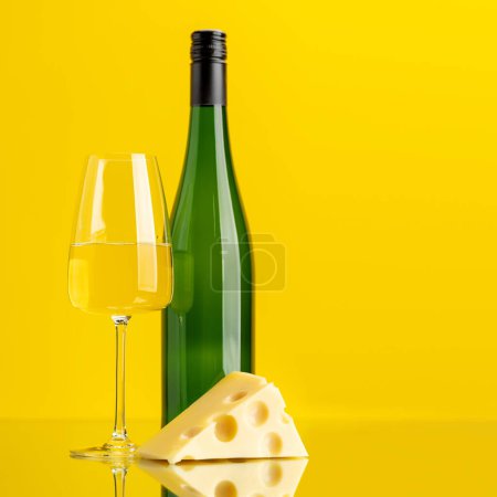 Photo for Aromatic white wine poured into a glass, accompanied by a tempting piece of cheese - Royalty Free Image