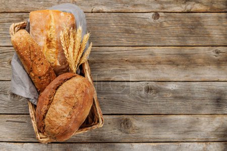 Téléchargez les photos : Variétés de pain variées dans un charmant panier, prêt à être dégusté. Pose plate avec espace de copie - en image libre de droit