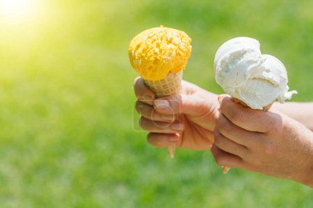 Téléchargez les photos : Les mains de la femme tenant de la crème glacée rafraîchissante dans des cônes de gaufres sont agrémentées d'un soupçon de saveur citronnée. Avec espace de copie - en image libre de droit