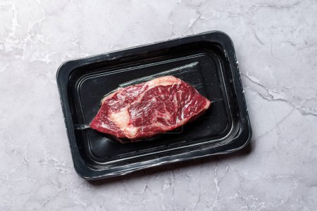 Téléchargez les photos : Bifteck de côtelette de bœuf cru frais scellé dans un emballage sous vide, préservant sa qualité et sa fraîcheur - en image libre de droit