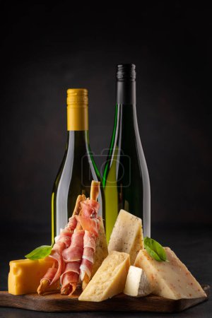 Téléchargez les photos : Antipasto board with various cheese and wine bottles - en image libre de droit