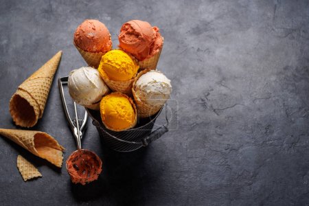 Téléchargez les photos : Des saveurs variées de crème glacée dans un délicieux cône de gaufre, un régal pour tous les papilles. Sur fond de pierre avec espace de copie - en image libre de droit