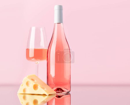 Photo for Aromatic rose wine poured into a glass, accompanied by a tempting piece of cheese. With copy space - Royalty Free Image