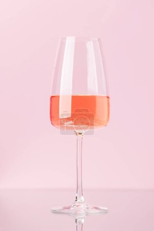 Photo for Rose wine in wine glass over rose background - Royalty Free Image