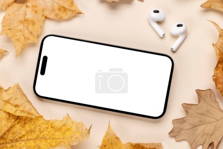 Foto de Smartphone con pantalla en blanco en una mesa rodeada de hojas naturales de otoño, maqueta de diseño perfecto - Imagen libre de derechos