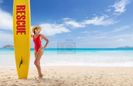Photo for Woman in red swimsuit stand with lifeguard surf rescue board on a tropical beach - Royalty Free Image