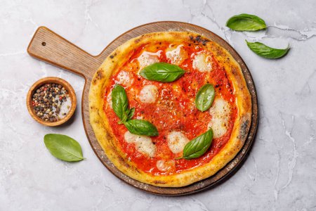 Téléchargez les photos : Pizza margarita maison, garnie de tomates fraîches, de fromage mozzarella et de feuilles de basilic aromatiques. Pose plate - en image libre de droit