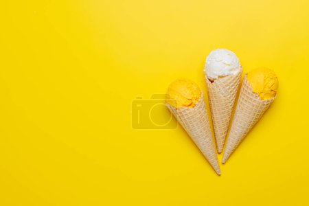 Foto de Surtido de sabores de helado en deliciosos conos de gofres, un regalo para todos los papilas gustativas. Sobre fondo amarillo con espacio de copia, plano - Imagen libre de derechos